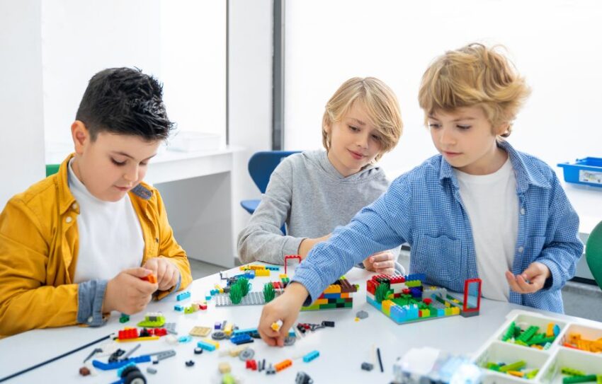 Three boys play with lego at a white table