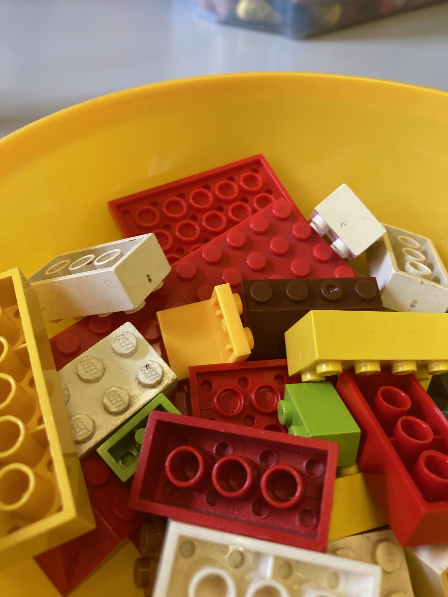 A yellow bowl filled with different coloured lego blocks