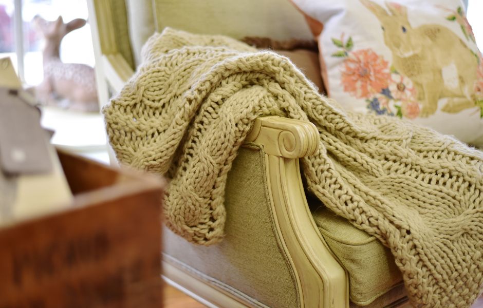 A green chair with a green throw placed over the arm.