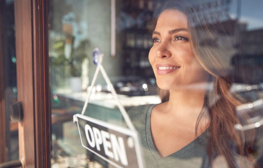 A woman looks through a shop door with an open sign