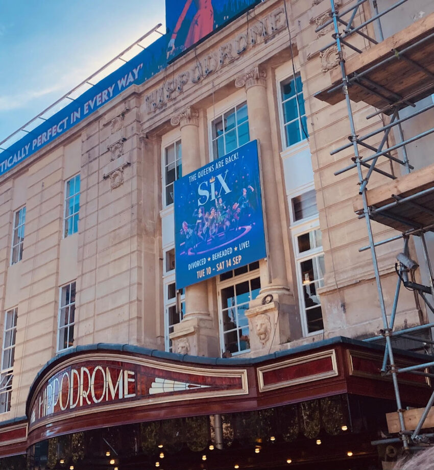 A picture of the front of the Bristol Hippodrome with red and gold signage and banner for the musical SIX.