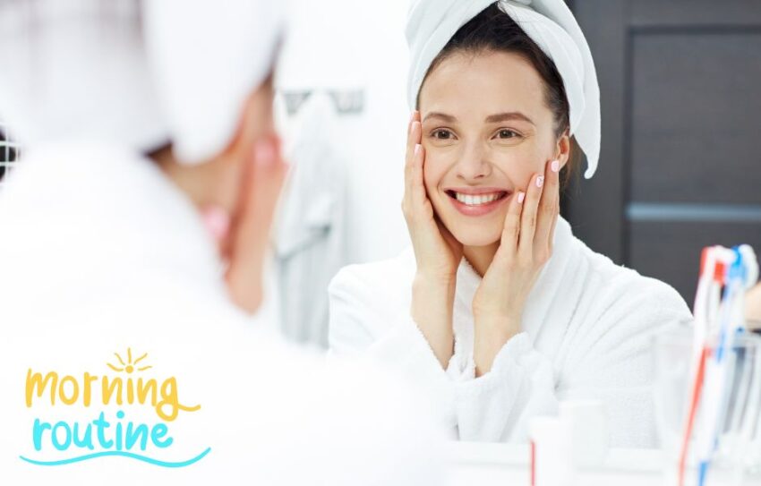 A woman is wearing a white dressing down and has her hair in a towel. She is looking in the mirror.