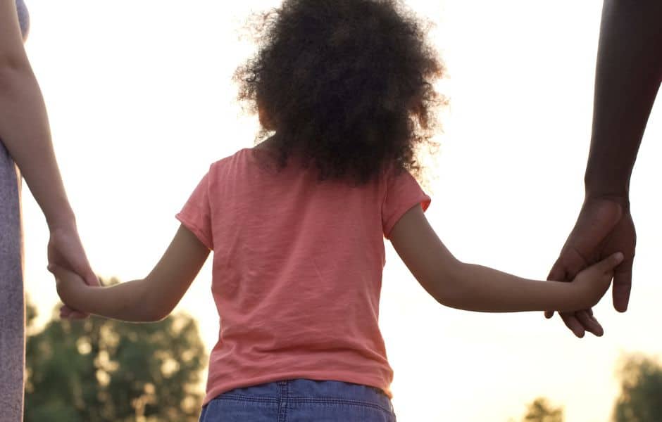 A child holding each of their parents hands